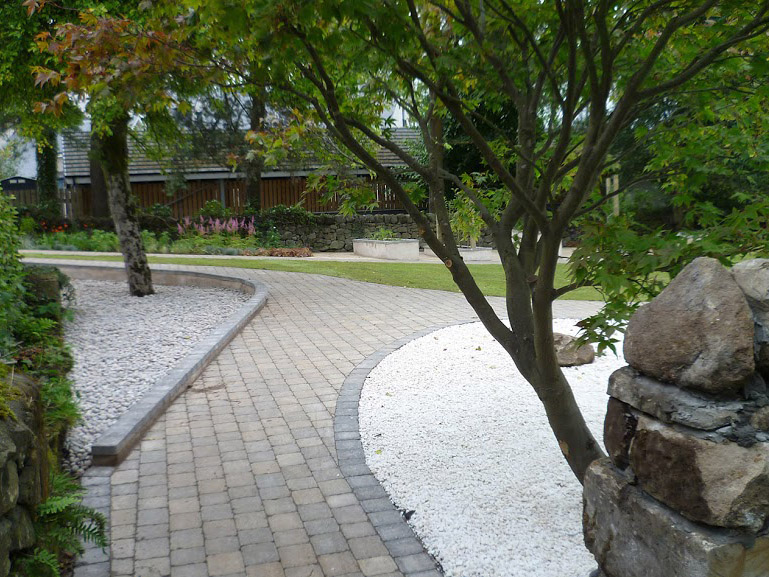 Showing smooth cobbled path curving past Japanese gravel planting bed